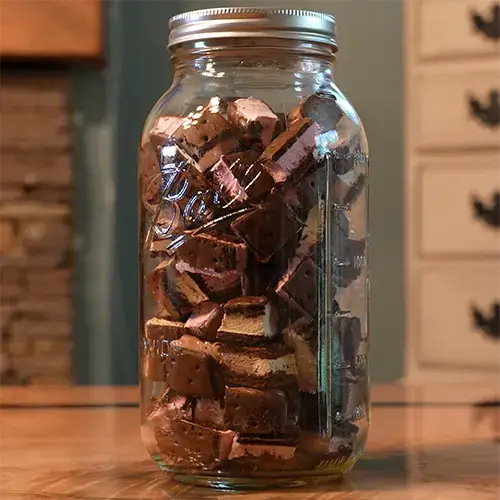 A mason jar packed with bite sized pieces of freeze dried Neapolitan ice cream sandwiches.