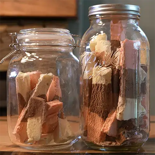 Two mason jars filled with freeze dried Neapolitan ice cream bars.