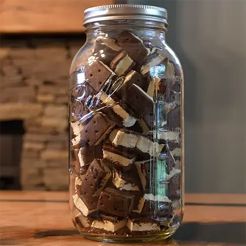 A mason jar packed with bite sized pieces of freeze dried ice cream sandwiches.