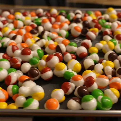A close up angled shot of tray full of puffed up, freeze dried Skittles.