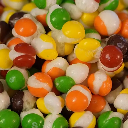 An array of colorful puffed up freeze dried skittles piled on top of each other.