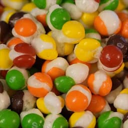 An array of colorful puffed up freeze dried skittles piled on top of each other.
