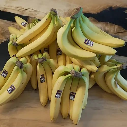 A large group of bananas stacked on top of each other sitting on a wooden table.