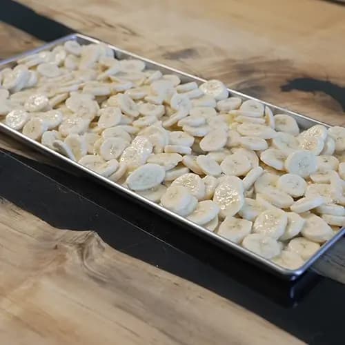 A Harvest Right medium sized tray full of banana slices that are coated in lemon juice.