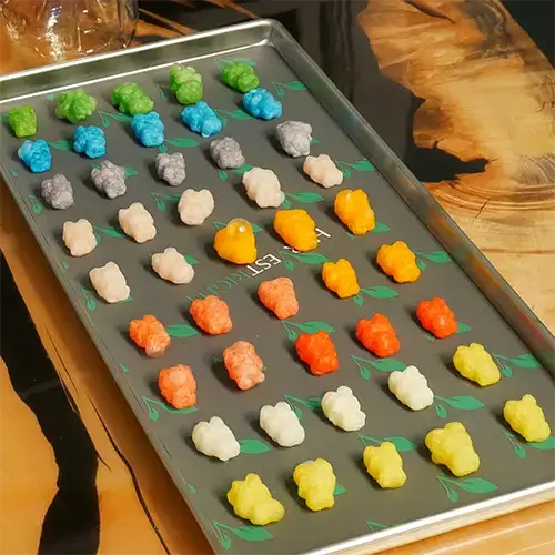A diagonal view of freeze dried gummy bears spread neatly on a medium Harvest Right freeze dry tray.