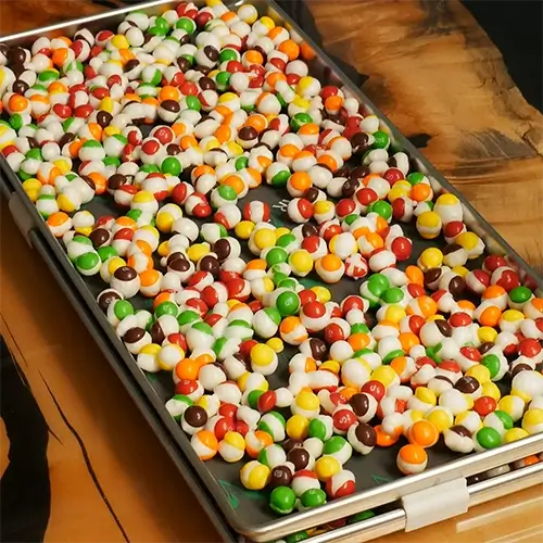 A tray full of puffed up, freeze dried skittles in a diagonal position.