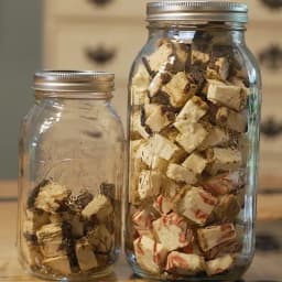 Two mason jars filled with various sizes of freeze dried cheesecake bites. 