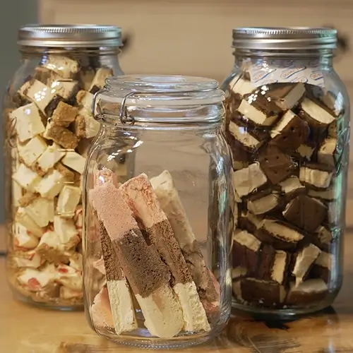 three mason jars filled with freeze dried desserts. From left to right, cheesecake bites, neapolitan ice cream, and ice cream sandwiches.