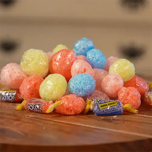 A stack of large freeze dried Jolly Ranchers surrounded by several packaged Jolly Ranchers.