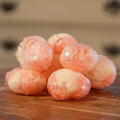 A stack of large freeze dried Haribo Peaches on a wooden board.