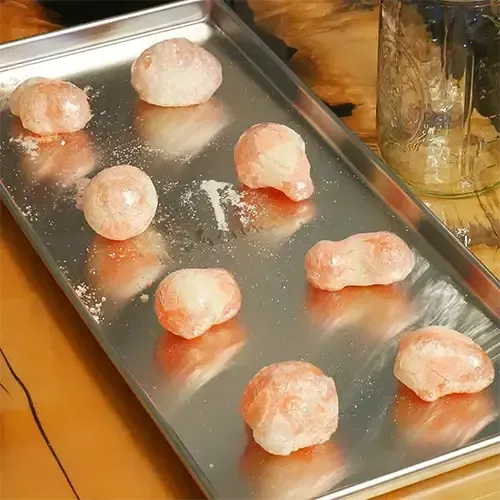 A diagonal view of eight freeze dried Haribo Peaches placed neatly in rows on a medium Harvest Right freeze dry tray.