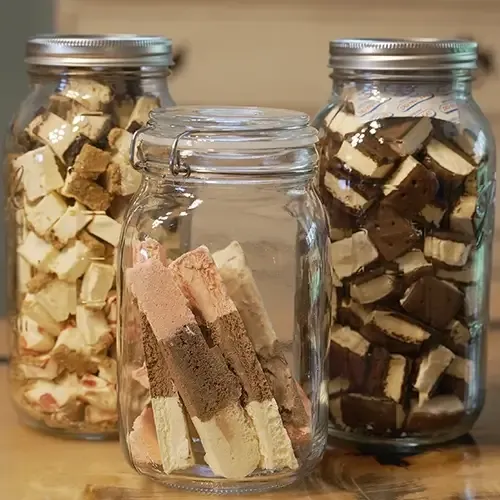 three mason jars filled with freeze dried desserts. From left to right, cheesecake bites, neapolitan ice cream, and ice cream sandwiches.